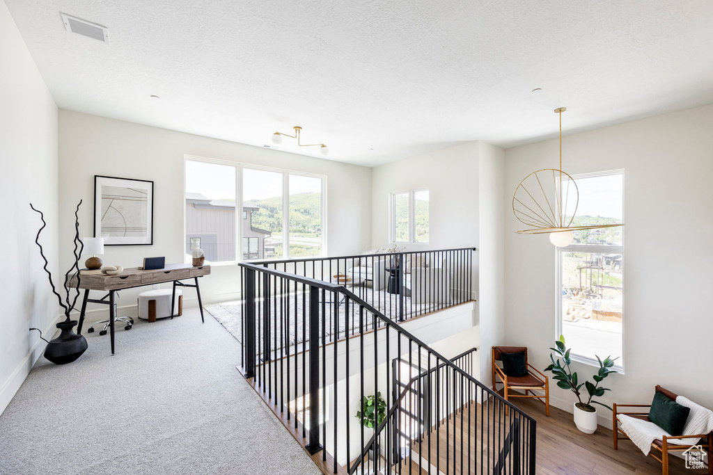 Hallway featuring an office area, baseboards, an upstairs landing, and a chandelier
