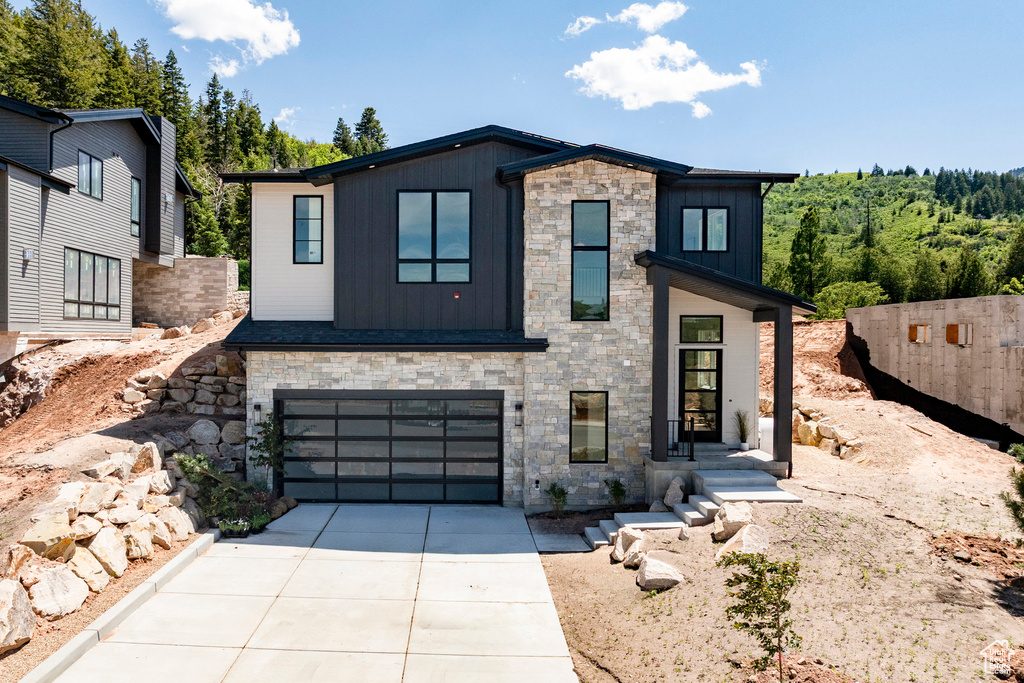Modern home with stone siding, board and batten siding, and driveway
