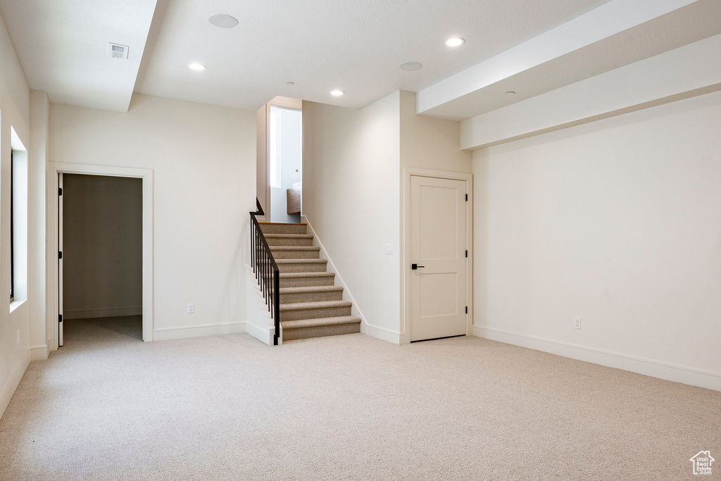 Below grade area with light colored carpet, stairway, recessed lighting, and baseboards