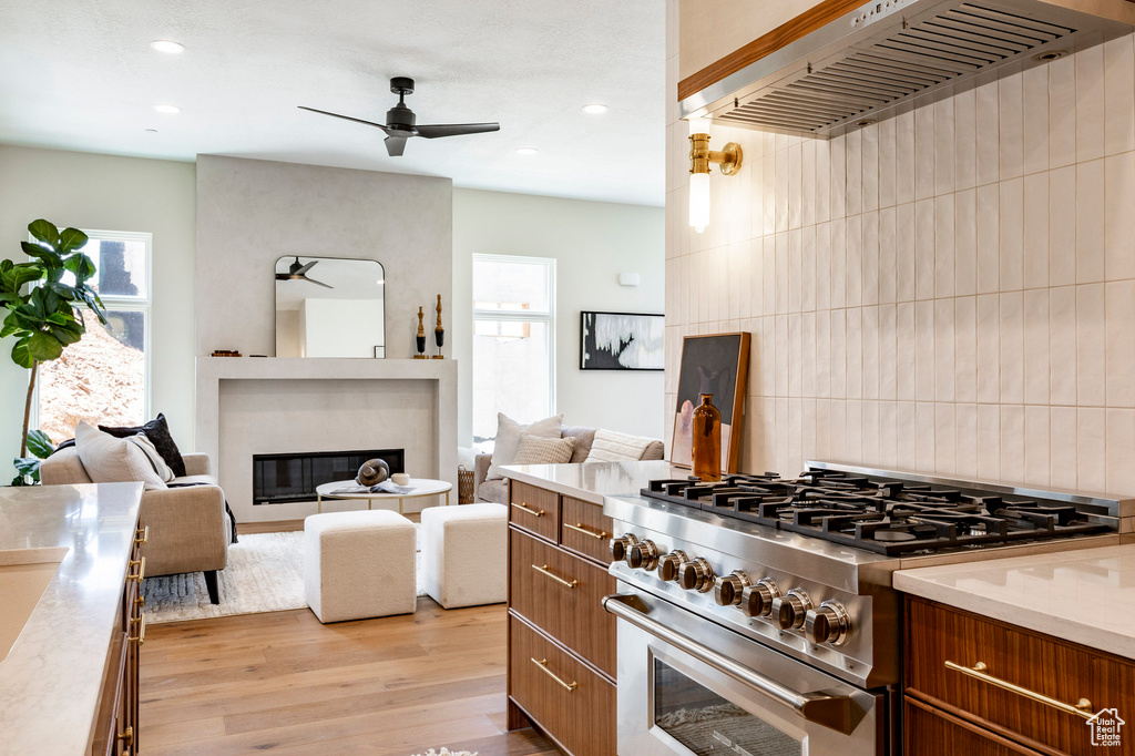 Kitchen featuring high end stainless steel range oven, ceiling fan, custom exhaust hood, light wood-style flooring, and recessed lighting