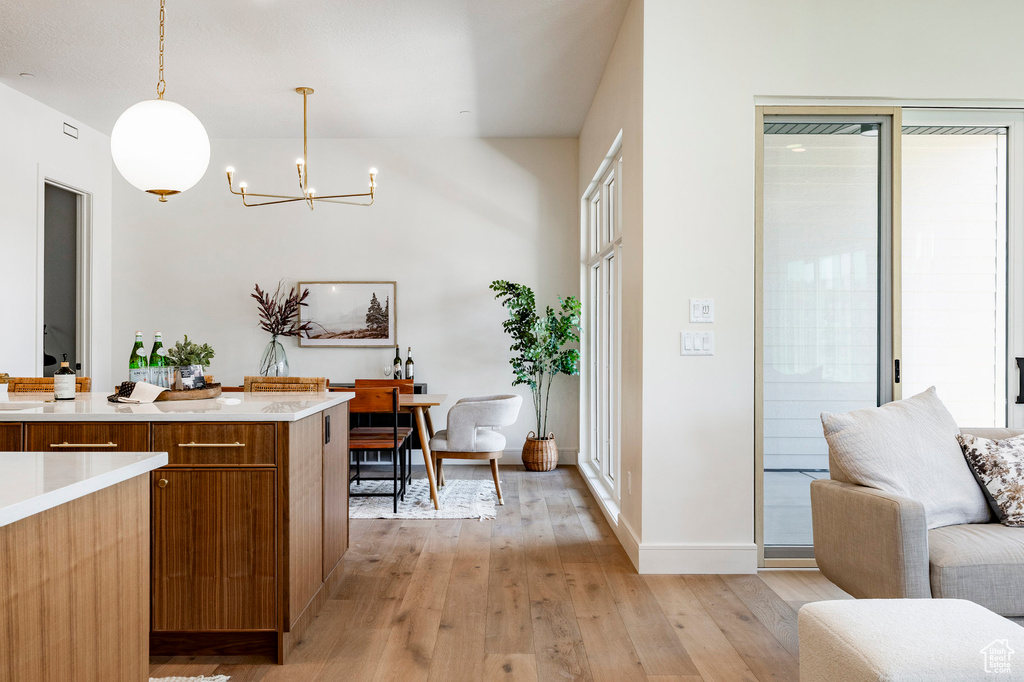 Kitchen featuring a chandelier, brown cabinetry, light wood finished floors, light countertops, and open floor plan