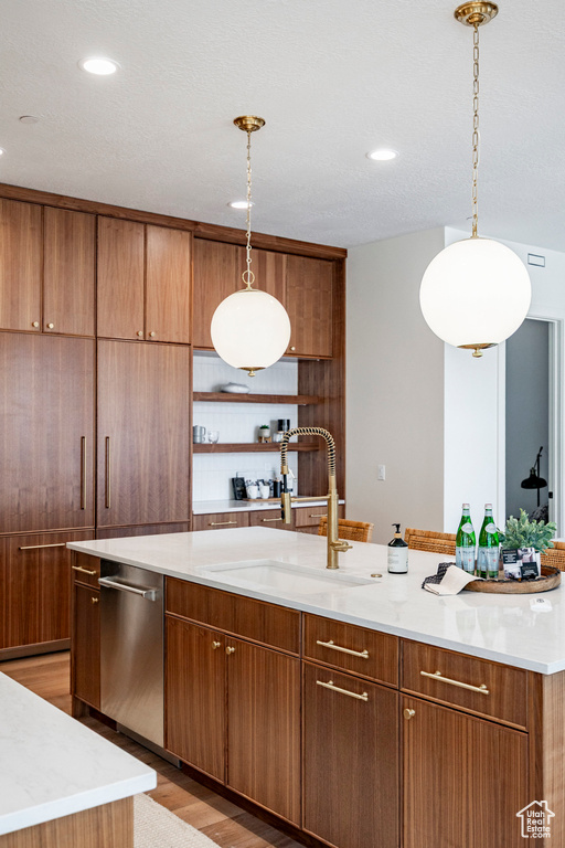 Kitchen featuring a sink, dishwasher, brown cabinets, and recessed lighting