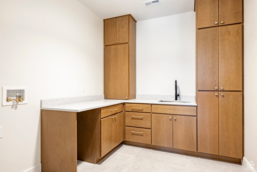 Kitchen featuring a sink, light countertops, and baseboards