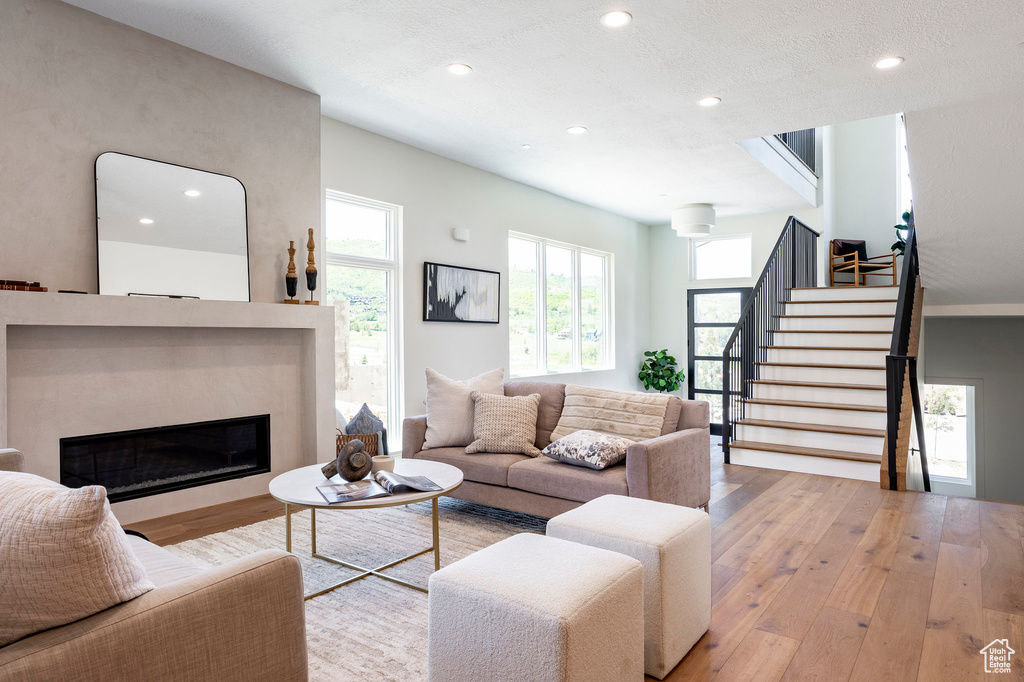 Living area featuring hardwood / wood-style flooring, recessed lighting, stairs, and a glass covered fireplace