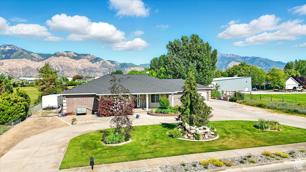 Ranch-style house featuring curved driveway, a mountain view, an attached garage, and brick siding