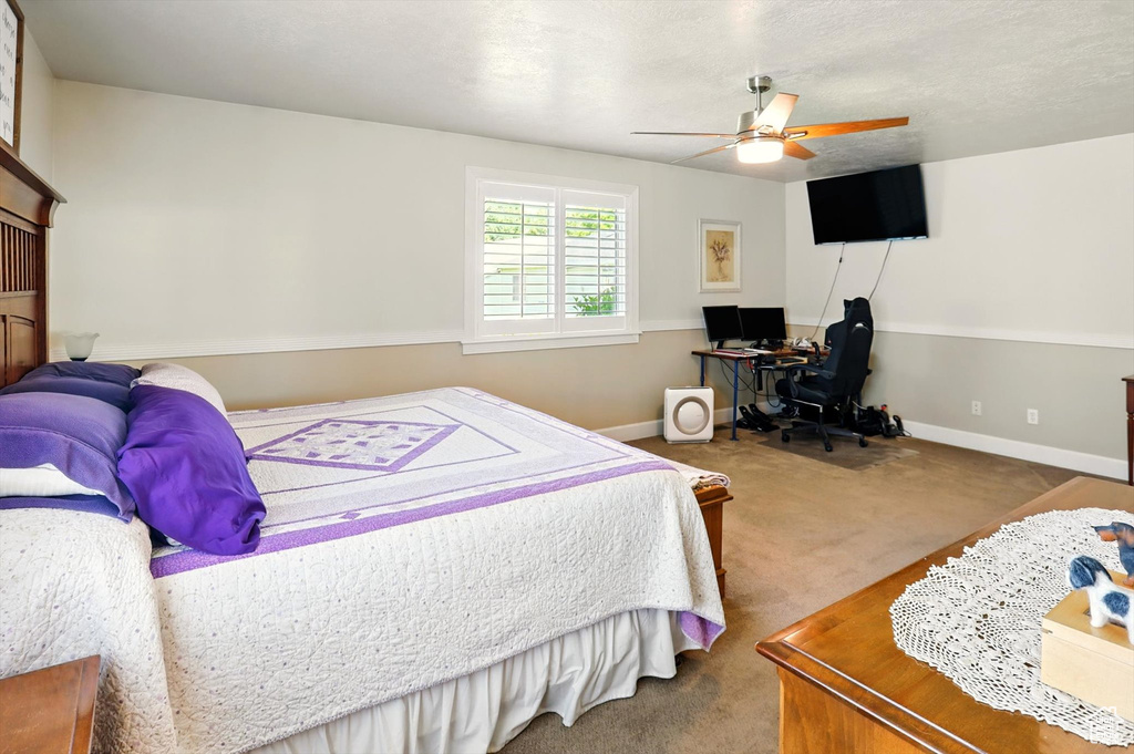 Bedroom with an office area, carpet, baseboards, and a ceiling fan