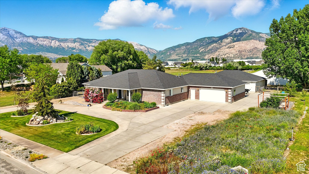 View of front of house with concrete driveway, an attached garage, a mountain view, and brick siding