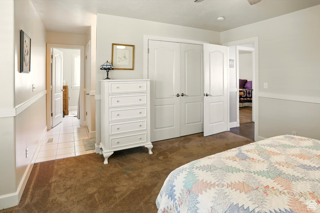 Carpeted bedroom with a closet, baseboards, and tile patterned floors