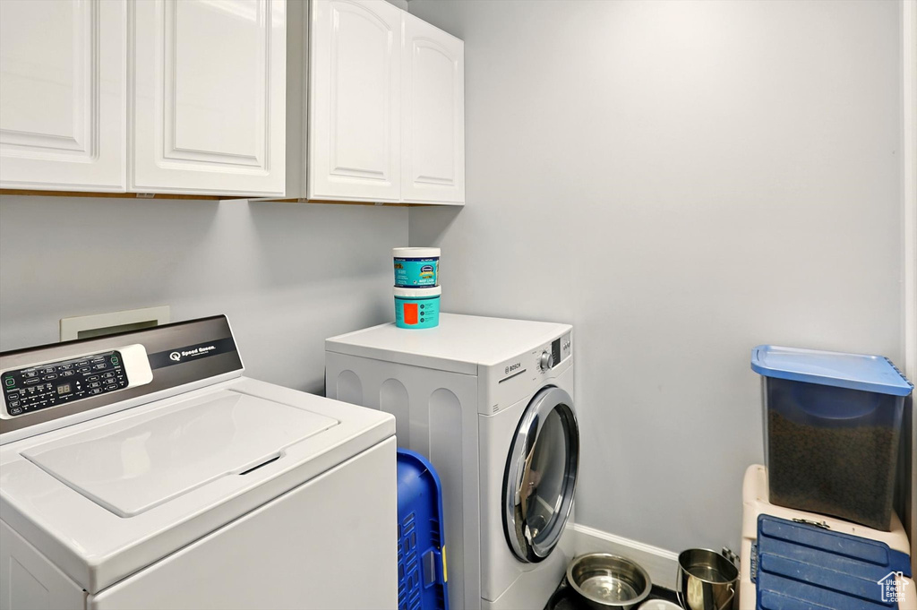 Washroom featuring separate washer and dryer, cabinet space, and baseboards