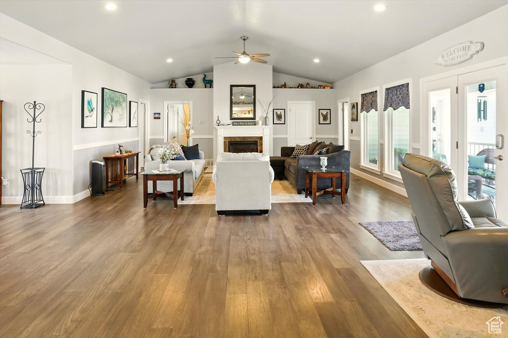 Living area with a ceiling fan, wood finished floors, vaulted ceiling, a fireplace, and recessed lighting