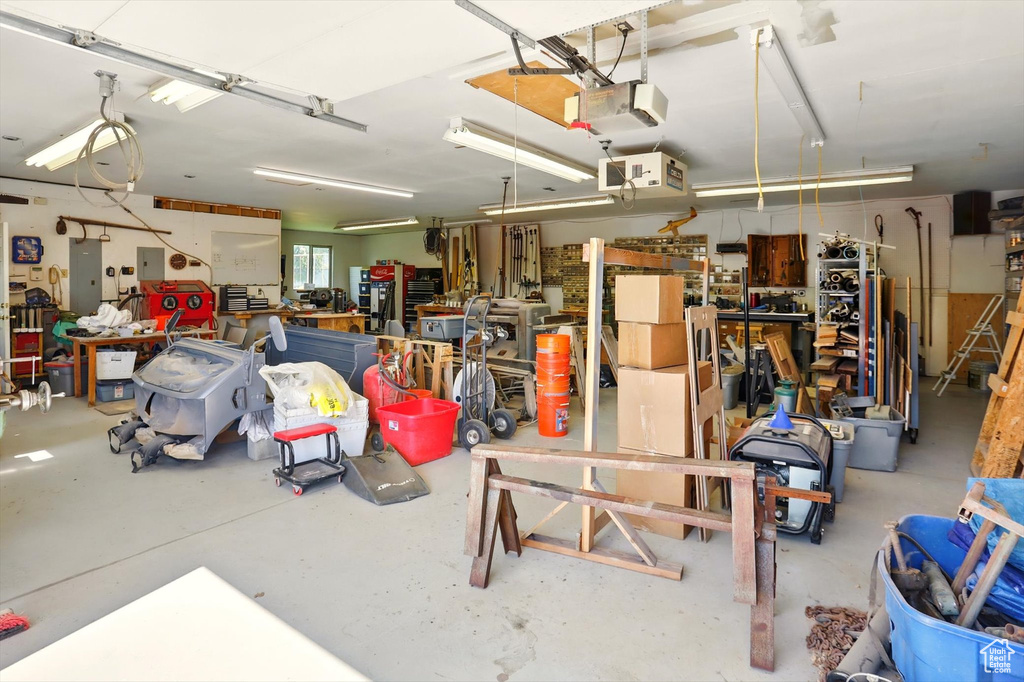 Garage featuring a workshop area, a garage door opener, and electric panel