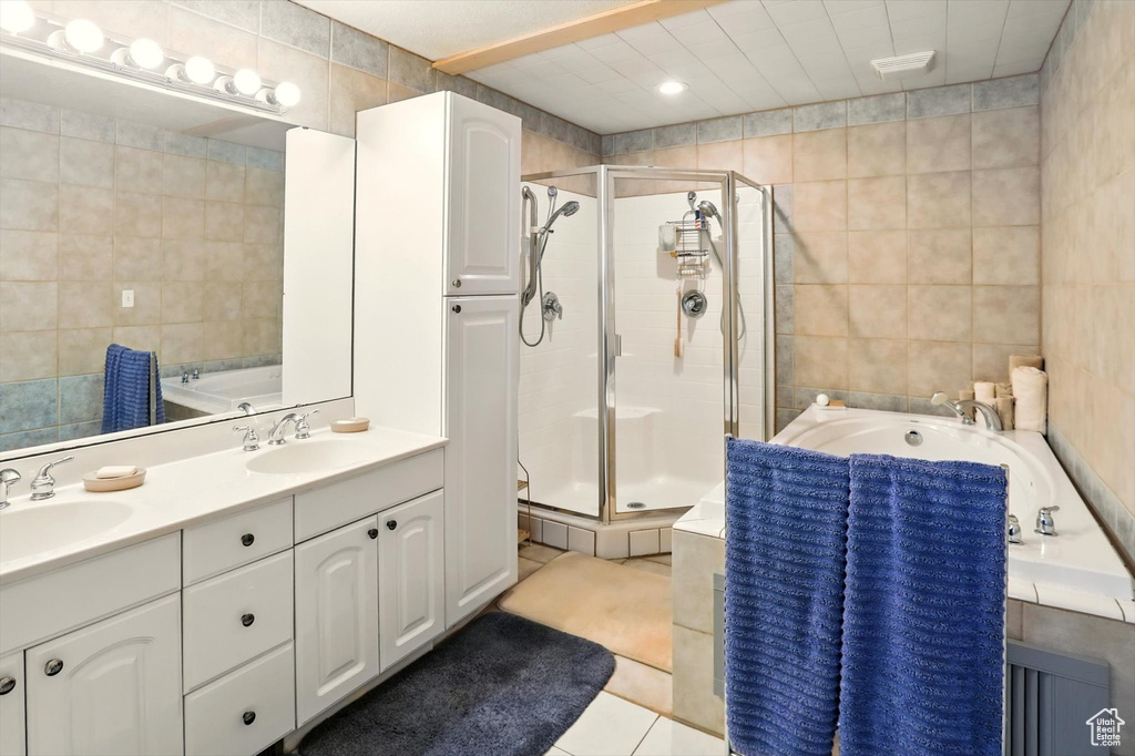 Bathroom featuring tile walls, a shower stall, a bath, tile patterned flooring, and double vanity