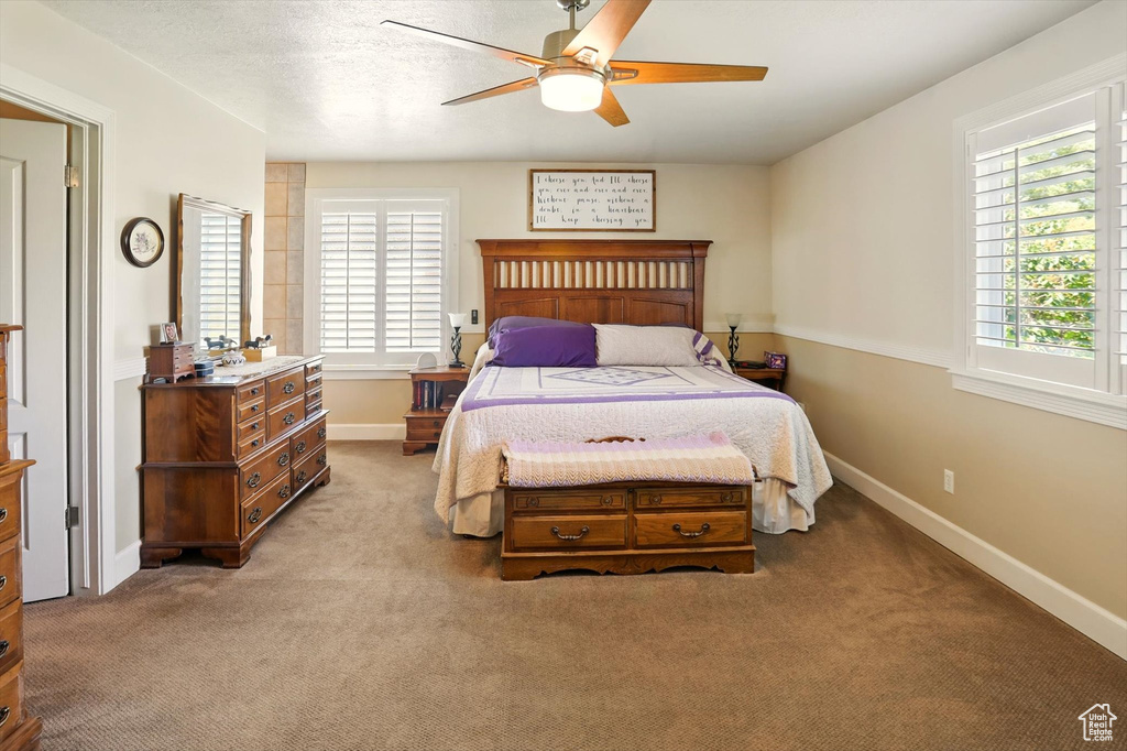 Bedroom featuring light colored carpet, baseboards, and a ceiling fan