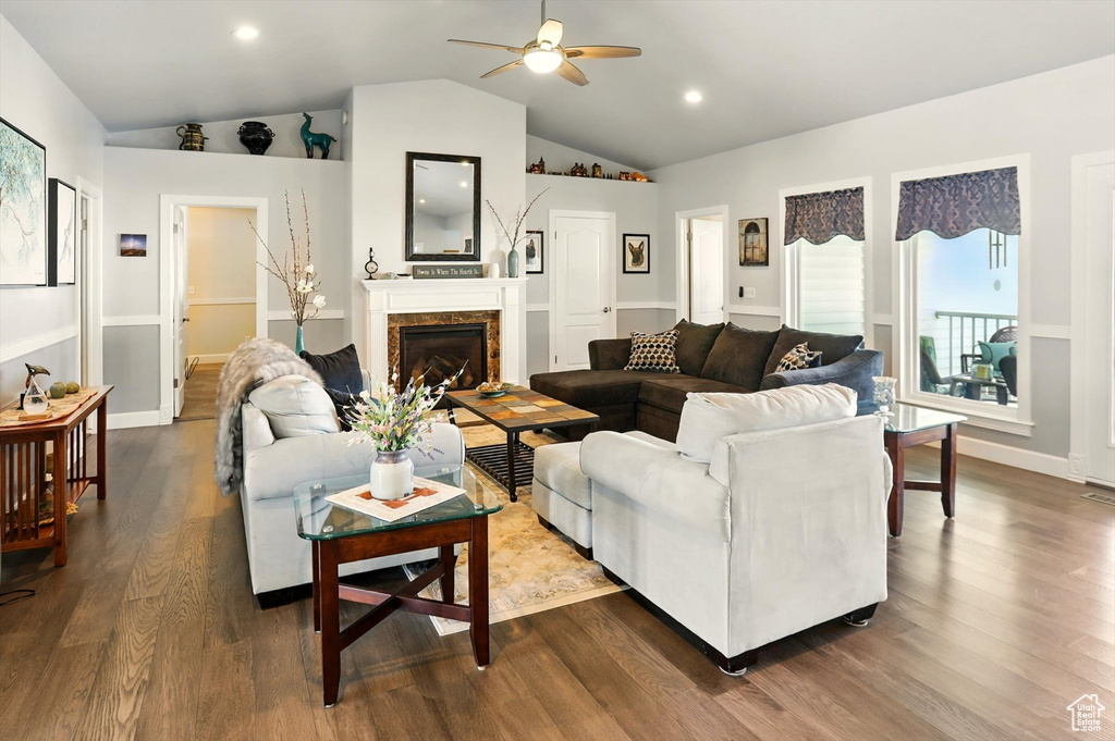 Living area featuring ceiling fan, lofted ceiling, dark wood-type flooring, a fireplace, and baseboards