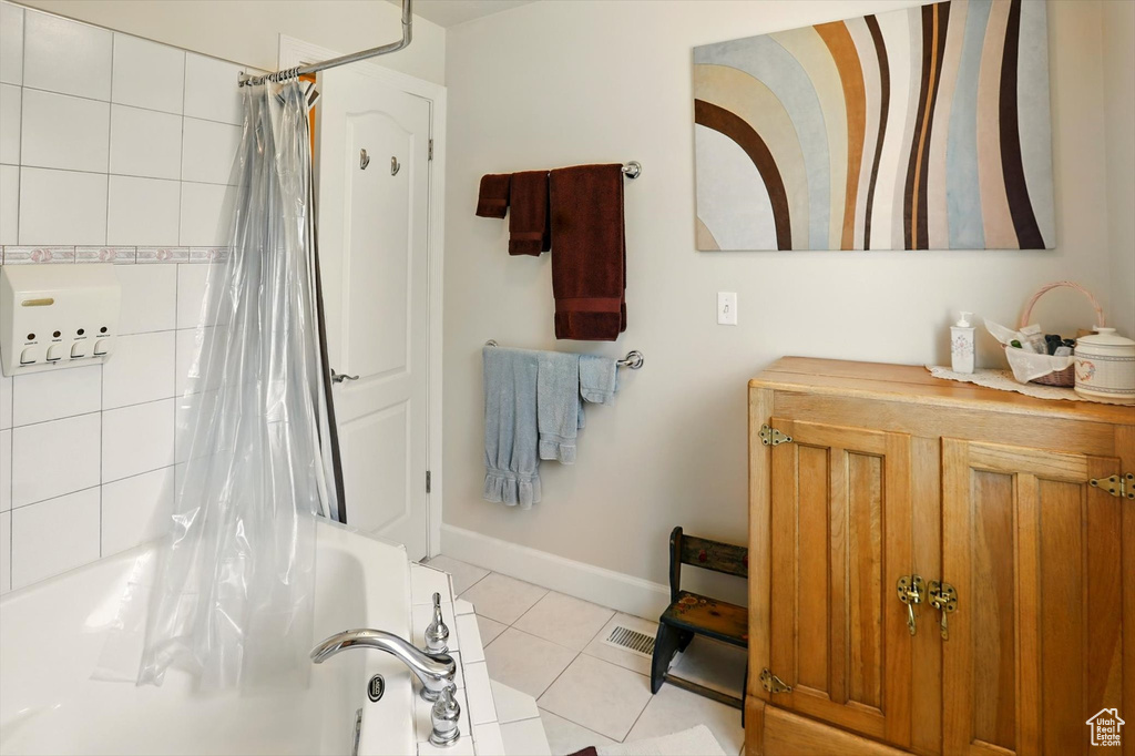 Bathroom with tile patterned flooring, shower / bathtub combination with curtain, baseboards, and vanity