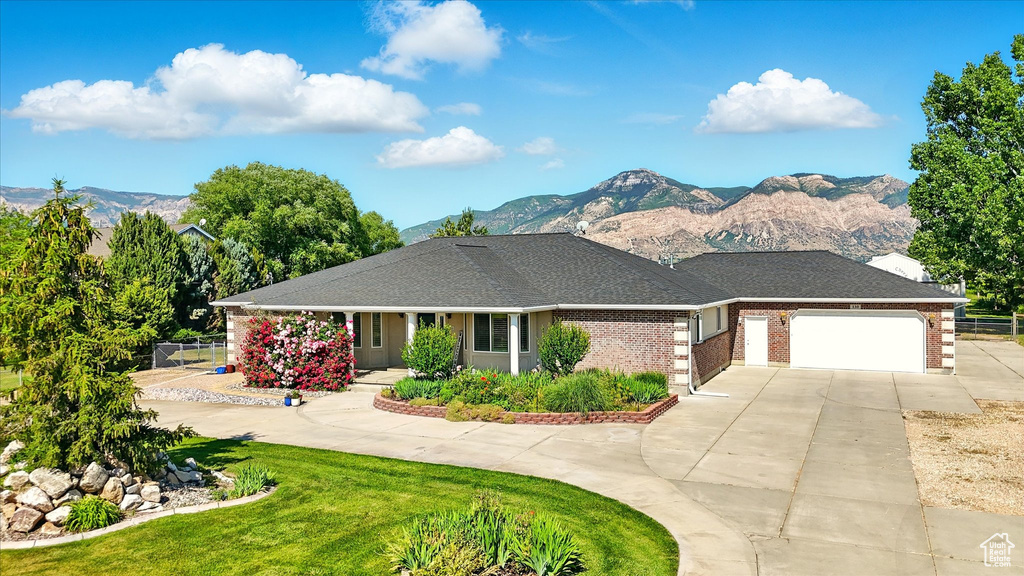 View of front facade featuring driveway, a mountain view, an attached garage, and brick siding