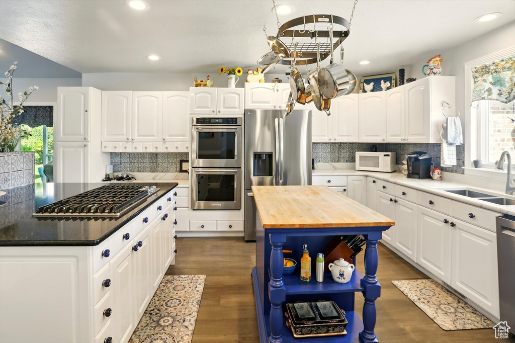 Kitchen featuring stainless steel appliances, wooden counters, a sink, a center island, and healthy amount of natural light