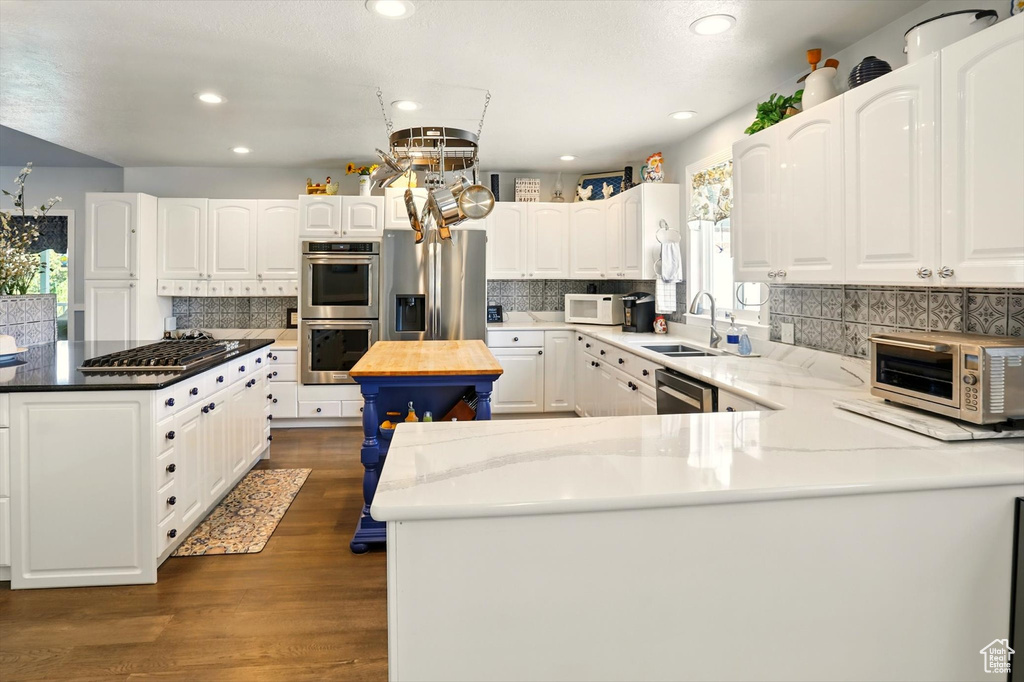 Kitchen with a center island, stainless steel appliances, backsplash, a sink, and recessed lighting