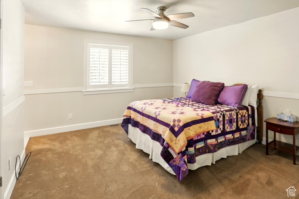 Carpeted bedroom with ceiling fan and baseboards