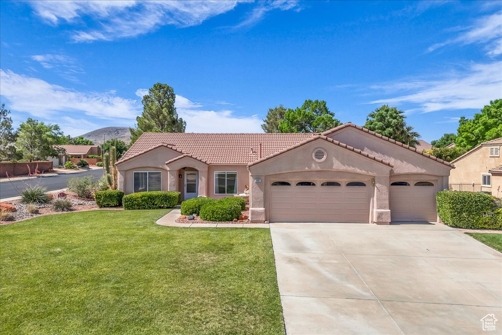 Mediterranean / spanish house featuring a tile roof, stucco siding, an attached garage, a front lawn, and driveway