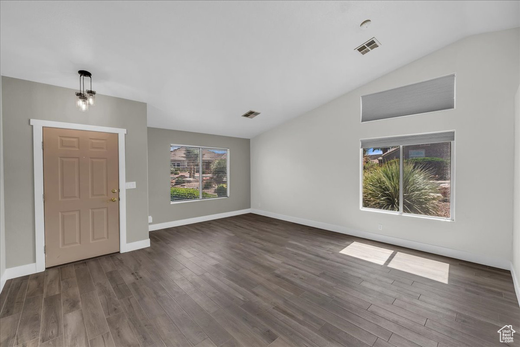 Entrance foyer with dark wood-style floors, vaulted ceiling, and baseboards