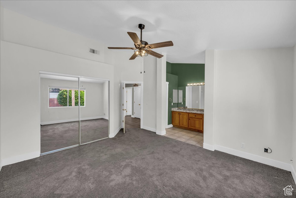 Unfurnished bedroom featuring carpet, baseboards, a closet, a high ceiling, and a ceiling fan