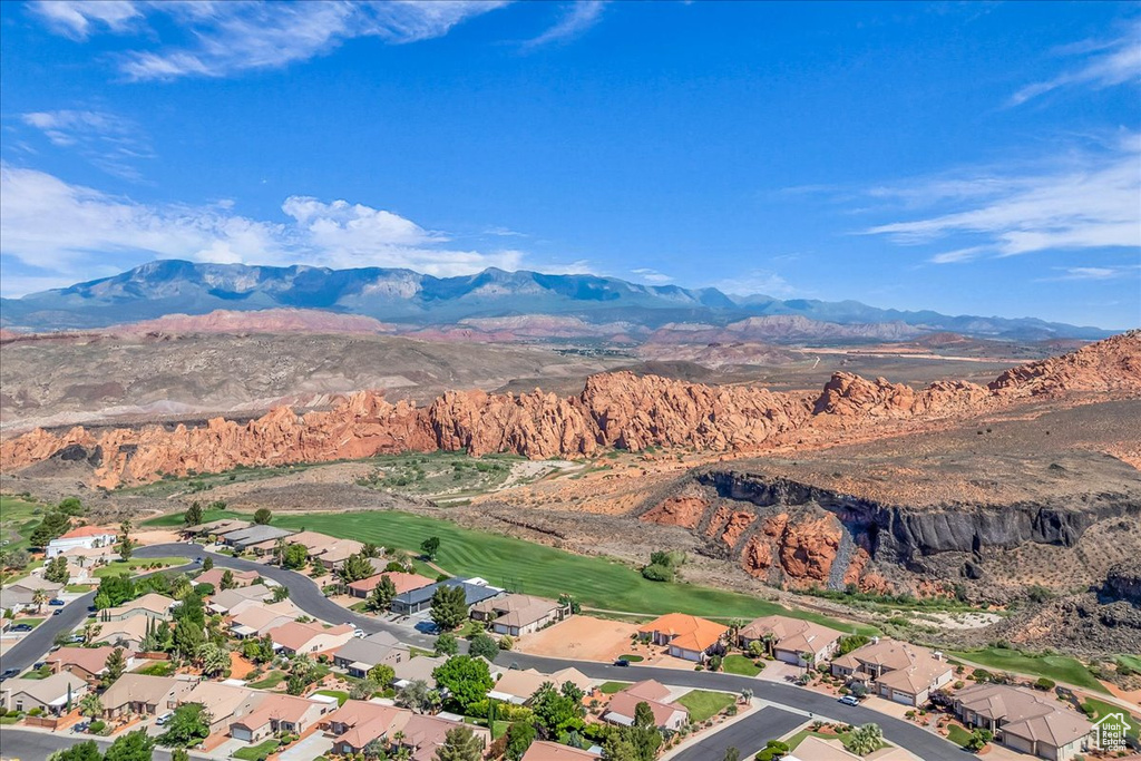 Aerial view of property's location with a mountainous background, a local golf course, and nearby suburban area