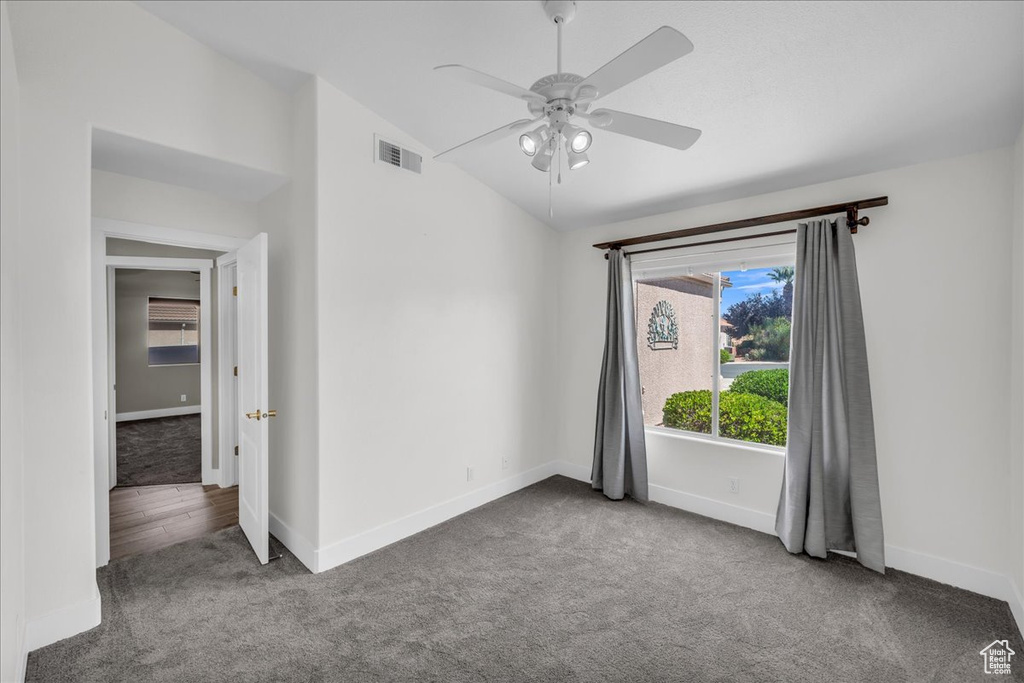 Spare room featuring carpet floors, vaulted ceiling, baseboards, and ceiling fan