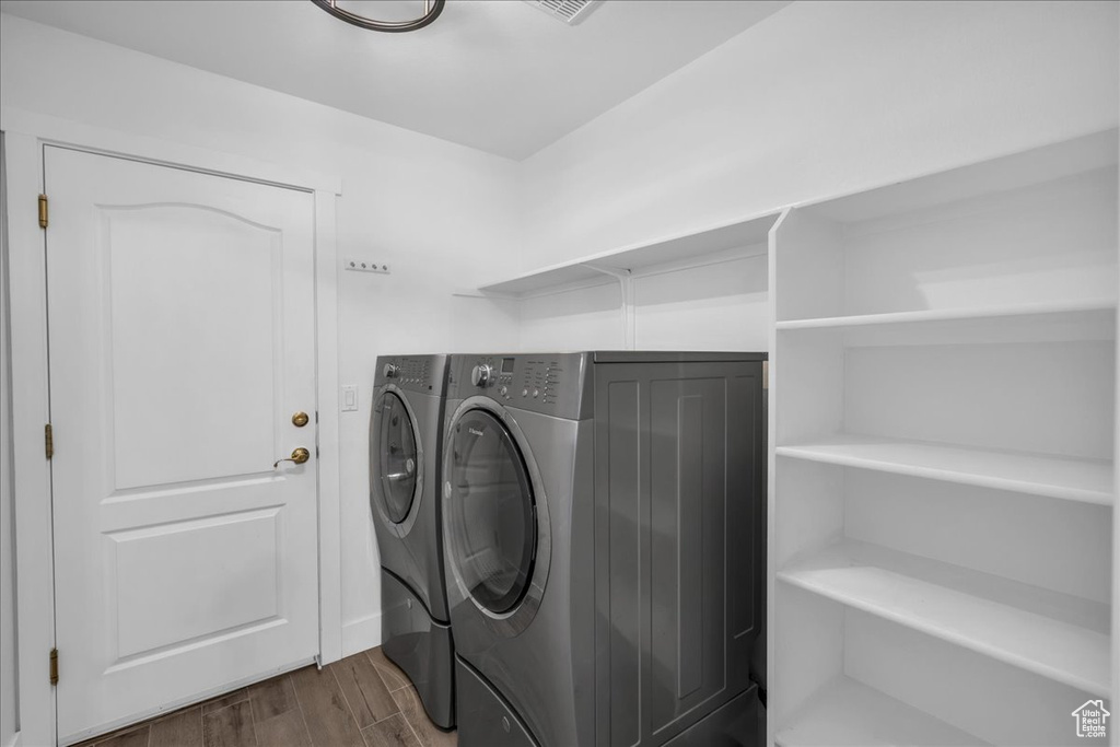Laundry room featuring washing machine and clothes dryer and dark wood-type flooring