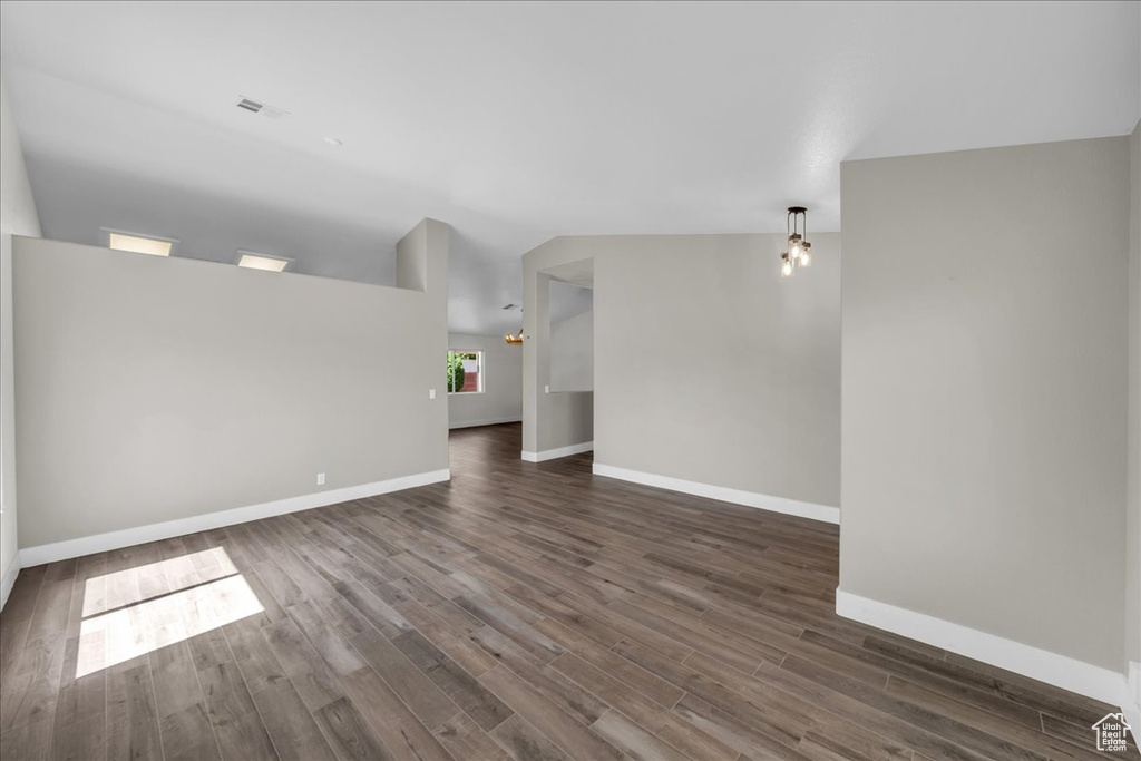 Spare room with dark wood finished floors, baseboards, and vaulted ceiling