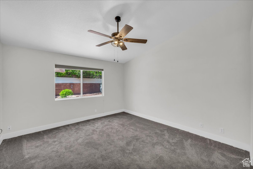 Carpeted empty room with a ceiling fan and baseboards