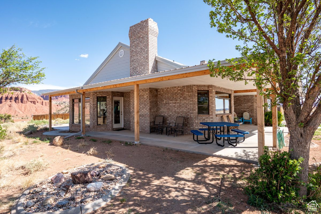 Back of property featuring brick siding, a patio, and a chimney