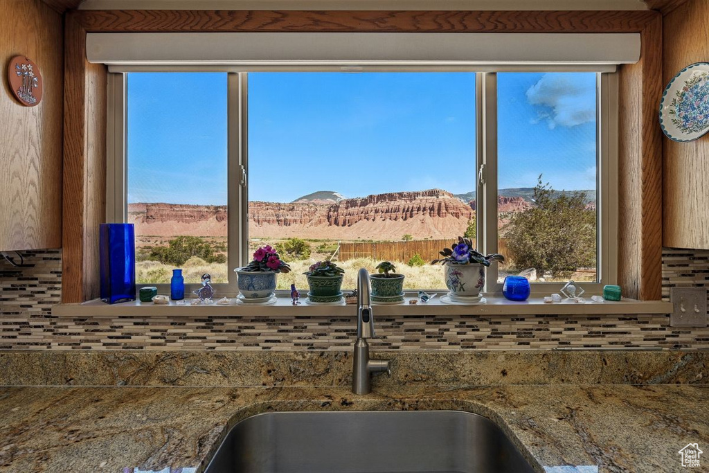 Kitchen view of a sink, decorative backsplash, a mountain backdrop, and stone countertops