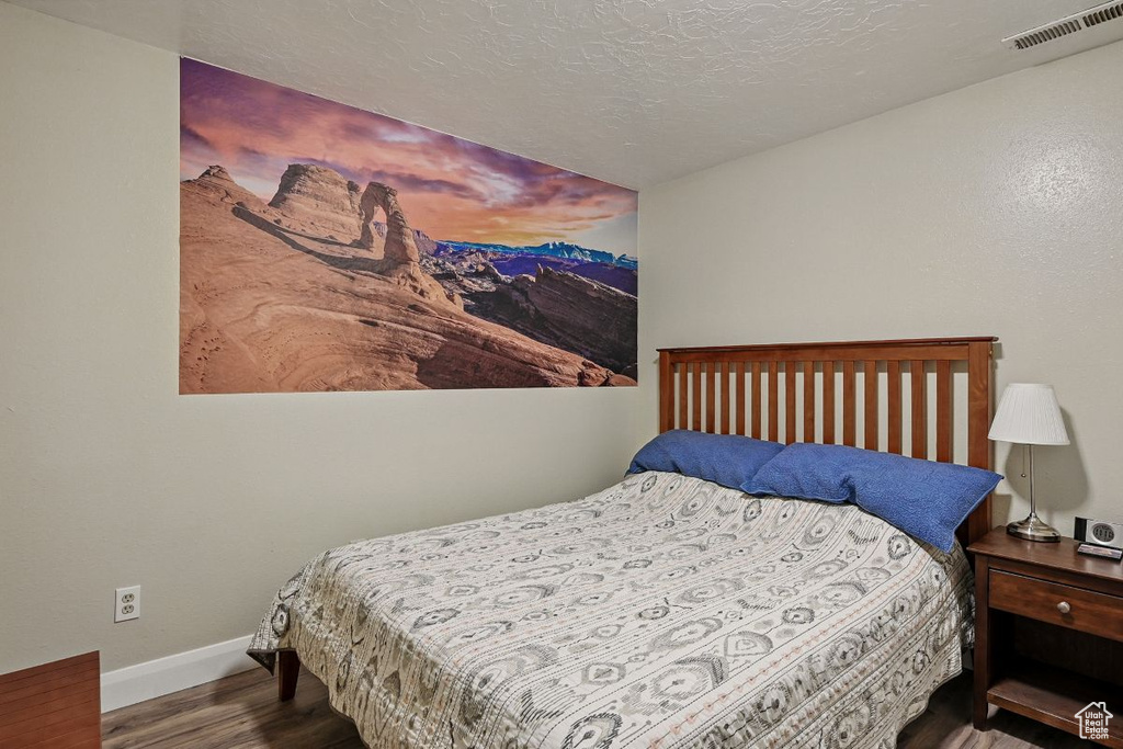 Bedroom with baseboards, wood finished floors, and a textured ceiling