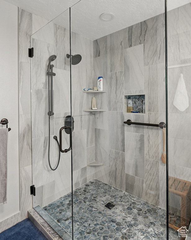 Full bathroom with a marble finish shower and a textured ceiling