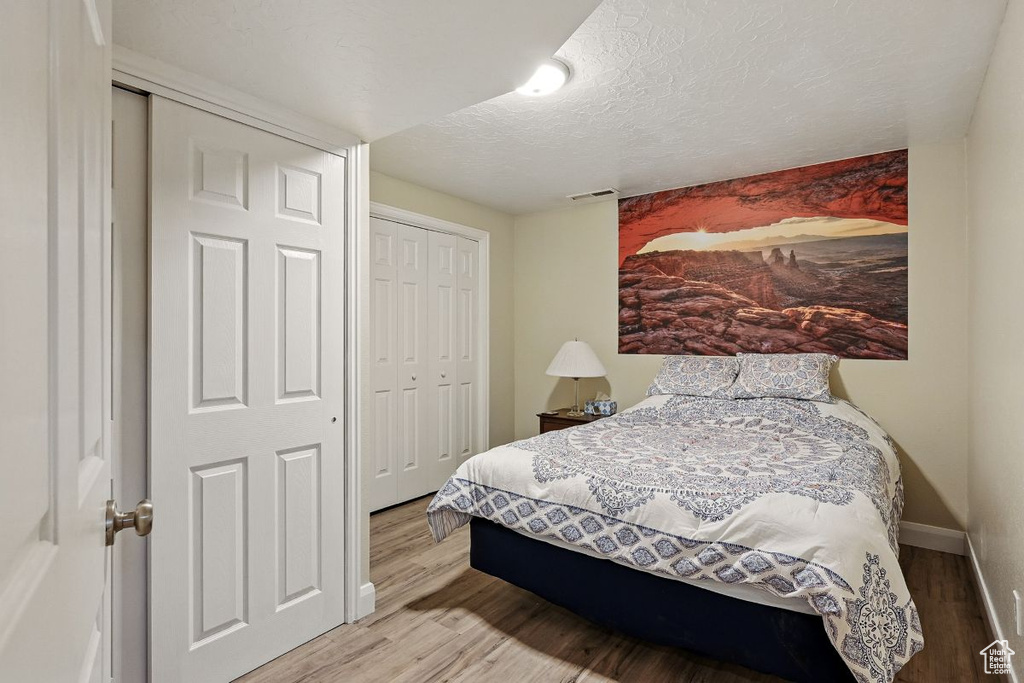 Bedroom featuring wood finished floors, a textured ceiling, a closet, and baseboards