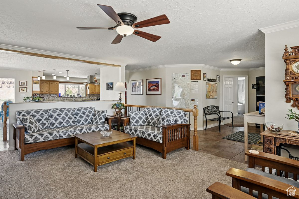 Living room featuring ceiling fan, a textured ceiling, ornamental molding, light tile patterned floors, and light carpet
