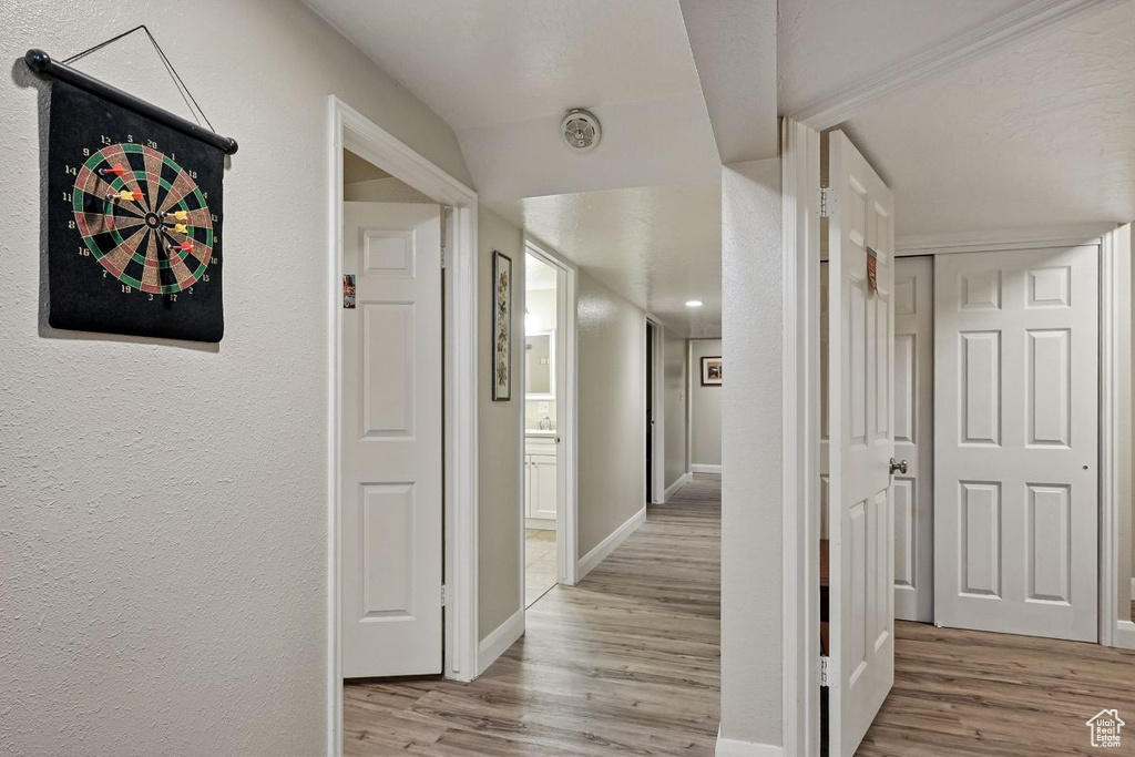 Hall featuring light wood-type flooring, baseboards, and a textured wall
