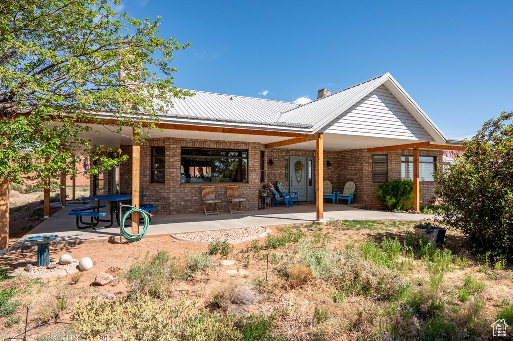 Rear view of property with brick siding, a patio, and metal roof
