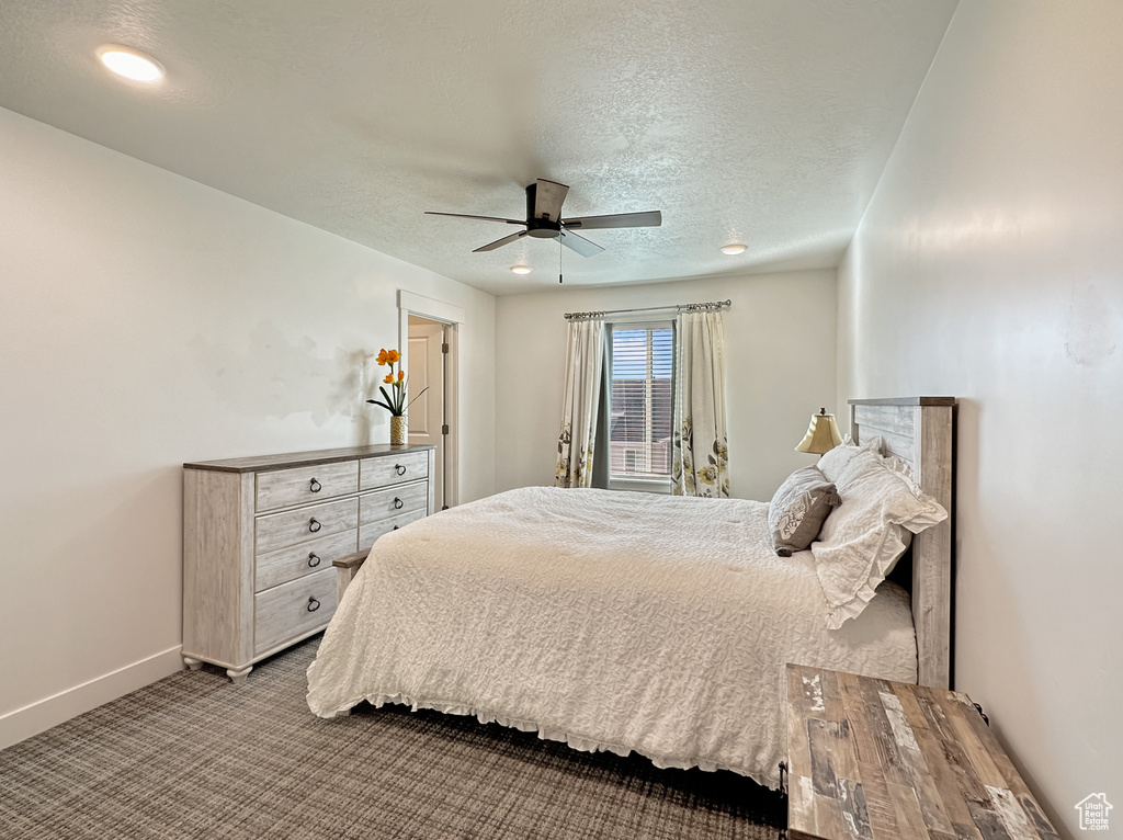 Carpeted bedroom featuring a textured ceiling, a ceiling fan, and baseboards
