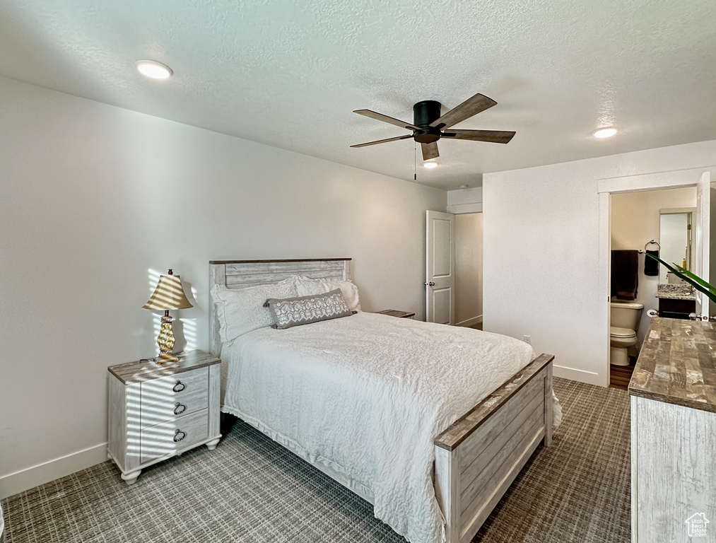 Bedroom with baseboards, dark colored carpet, a ceiling fan, a textured ceiling, and ensuite bath