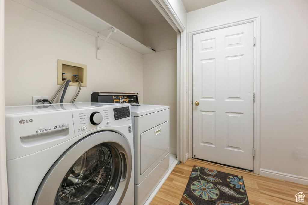 Laundry area with washer and dryer, light wood-style flooring, and baseboards
