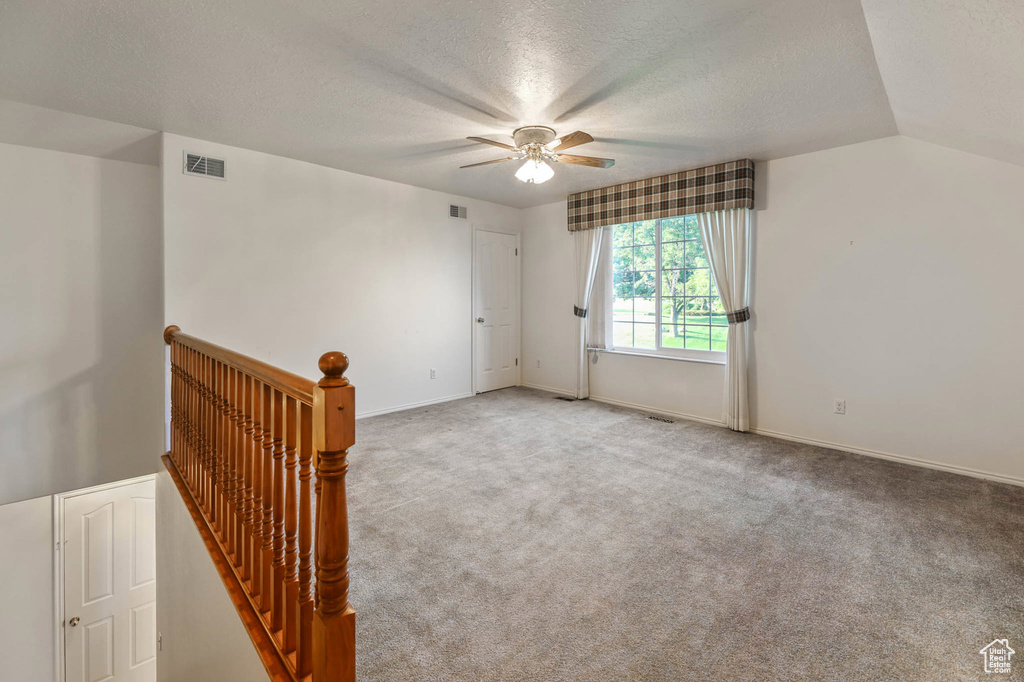 Unfurnished room featuring a textured ceiling, a ceiling fan, carpet flooring, and baseboards