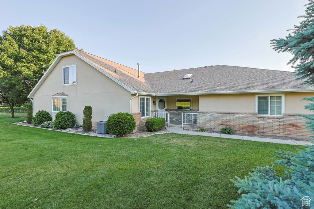 Single story home with stucco siding, a front lawn, brick siding, roof with shingles, and covered porch