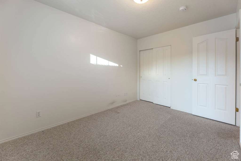 Unfurnished bedroom with carpet floors, a closet, and baseboards