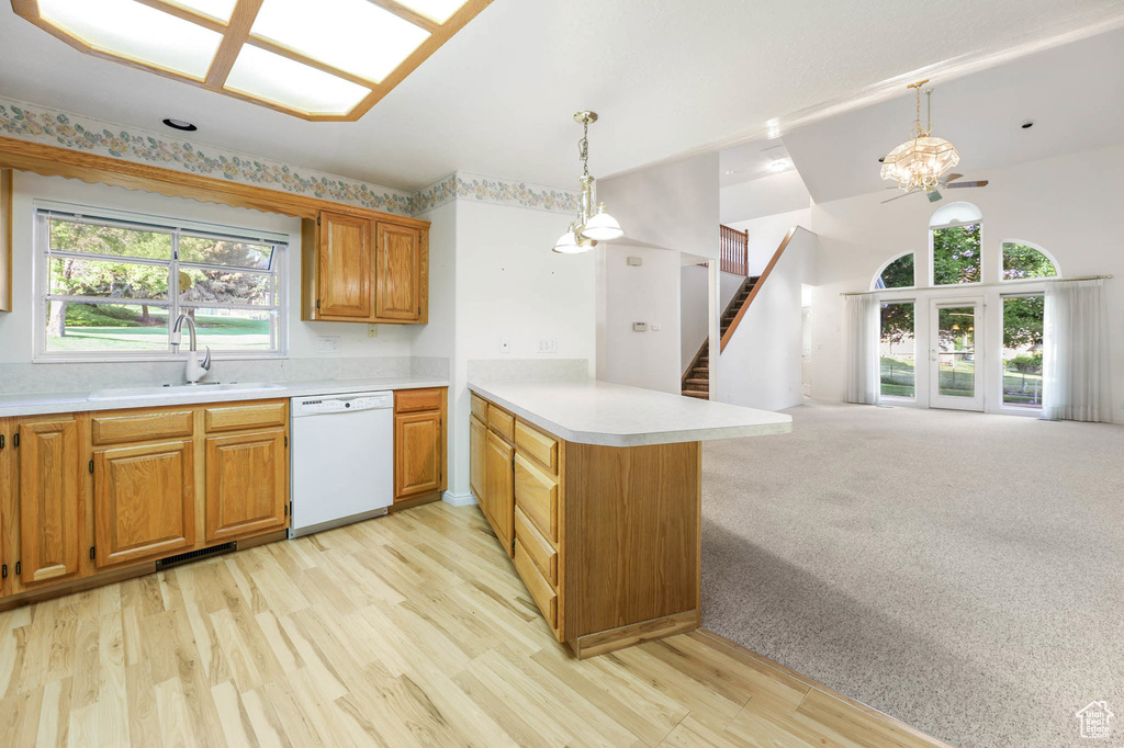 Kitchen with white dishwasher, a peninsula, a chandelier, light countertops, and open floor plan