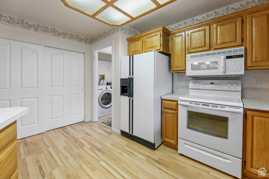Kitchen featuring white appliances, washer / dryer, light countertops, light wood-style flooring, and brown cabinets
