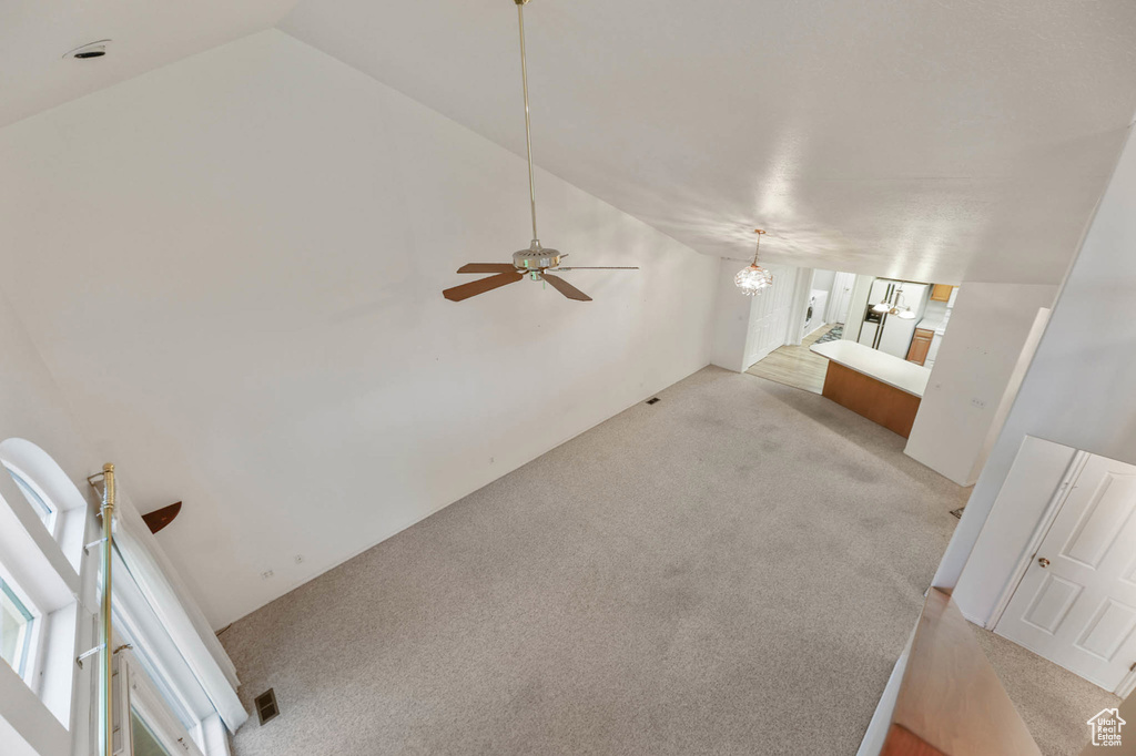 Unfurnished living room featuring vaulted ceiling, light colored carpet, and ceiling fan
