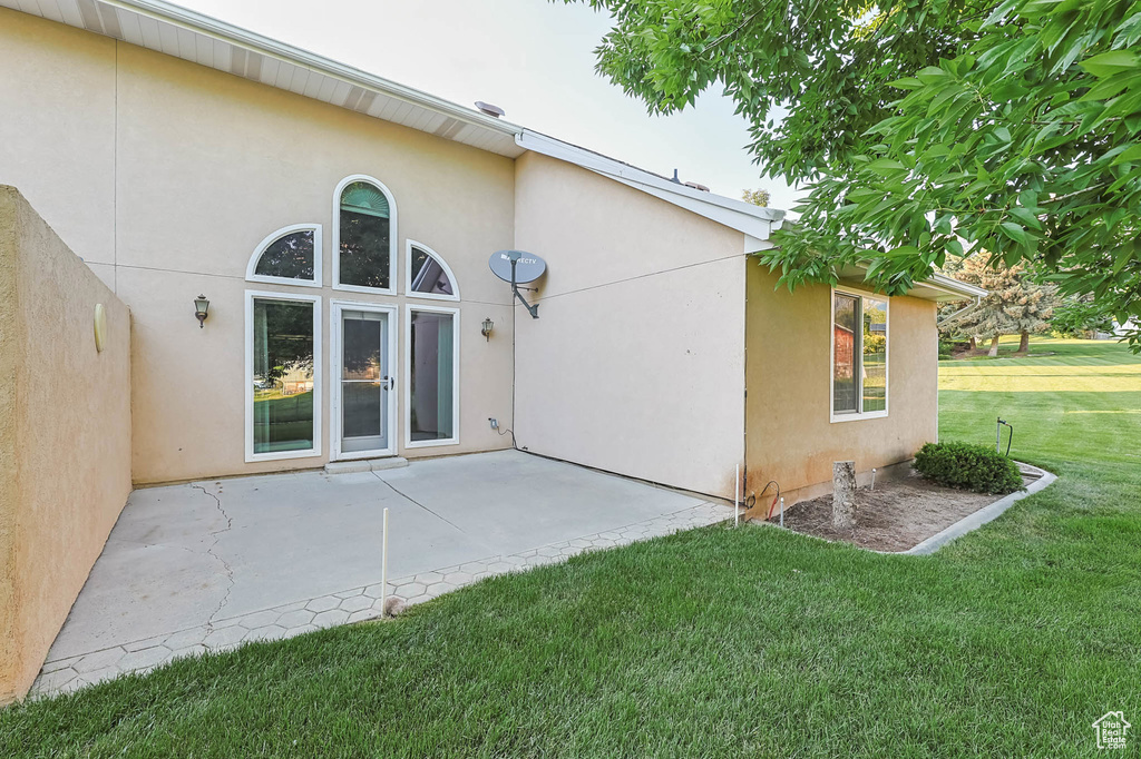 Rear view of property featuring stucco siding, a lawn, and a patio