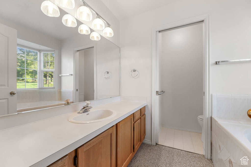 Bathroom with vanity, a garden tub, toilet, and speckled floor